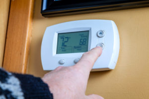 hand on wall-mounted thermostat